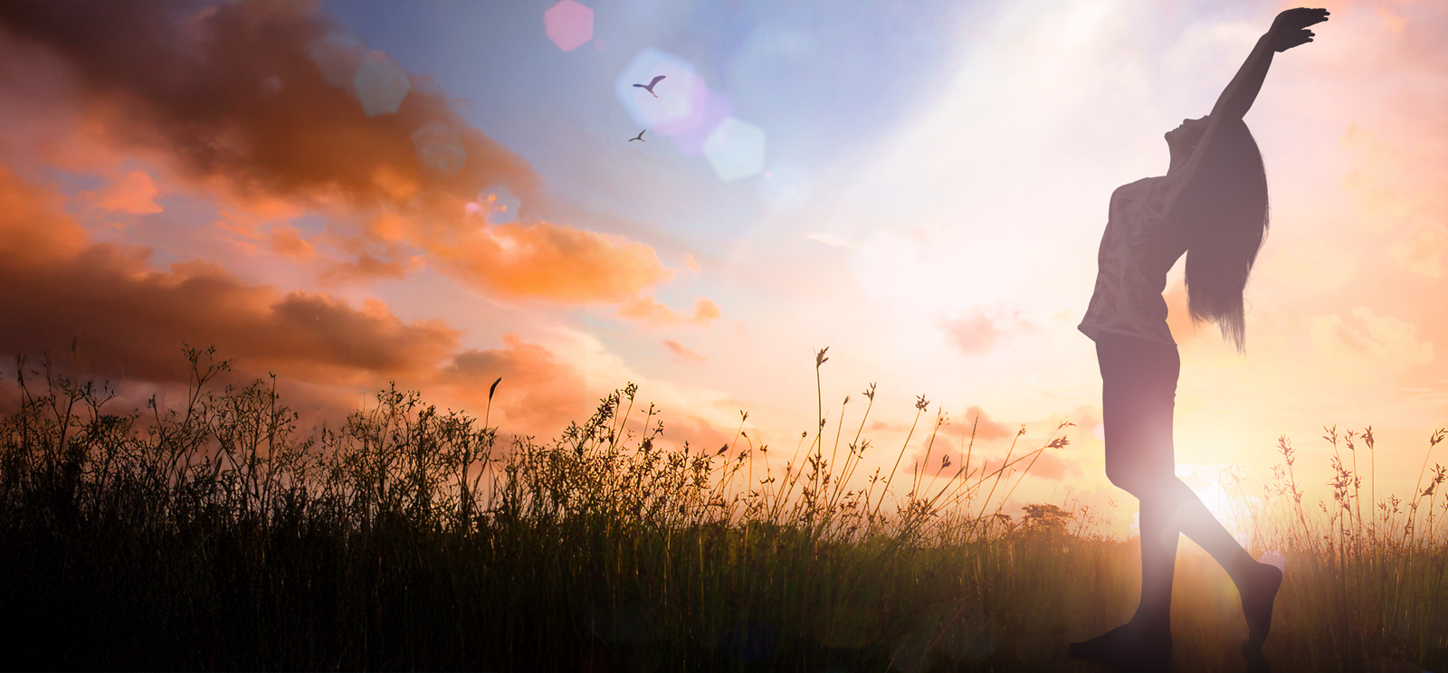 Woman reaching for the sky at sunset