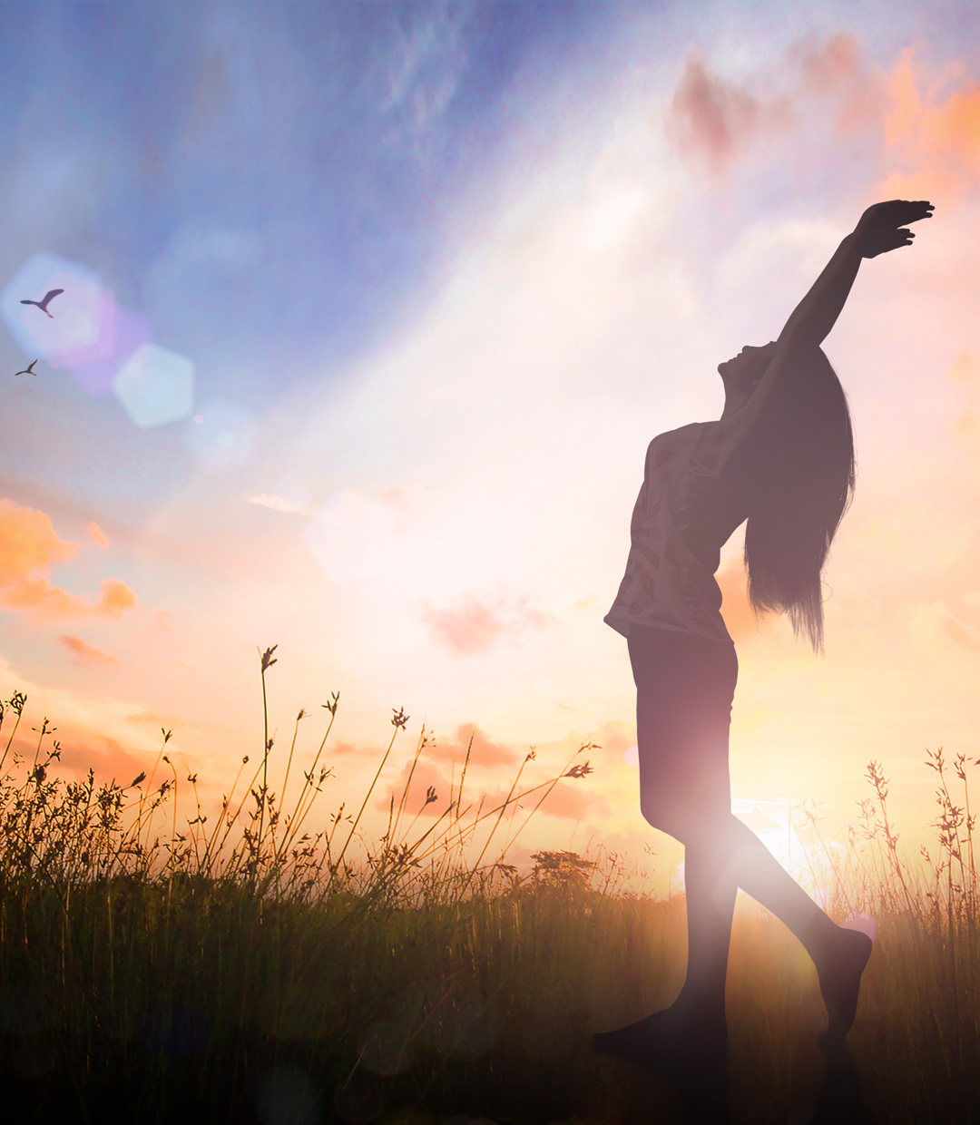 Woman reaching for the sky at sunset